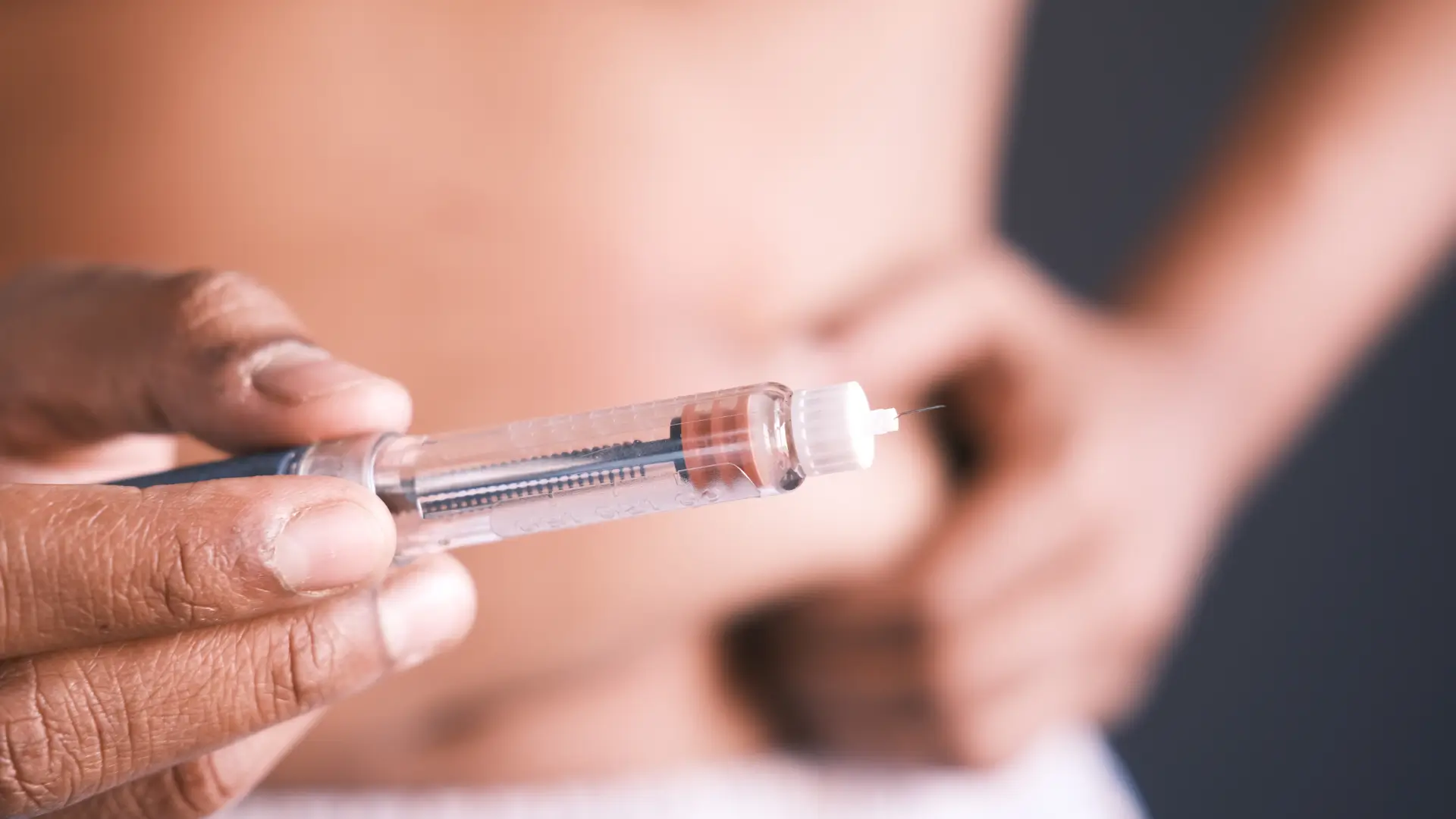 An individual holding an injector pen before injecting to abdomen.