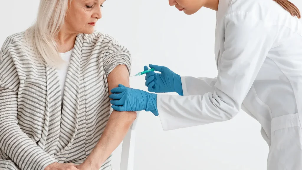 An older individual receiving an injection on their upper arm.