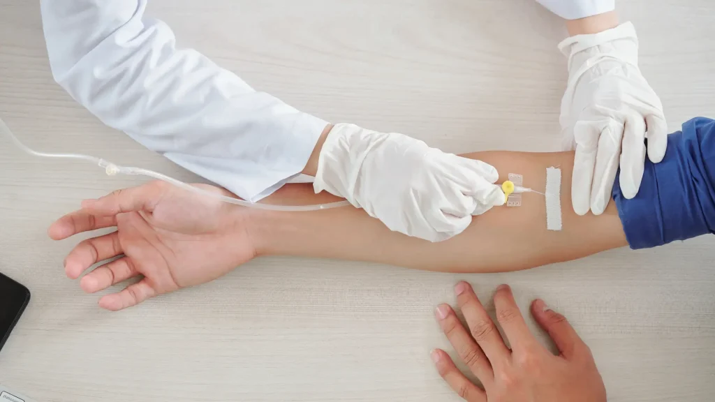 A medical professional preparing a patient's IV infusion.