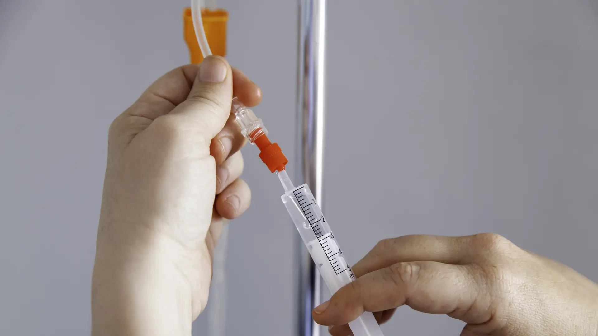 A provider administering medication through IV therapy.