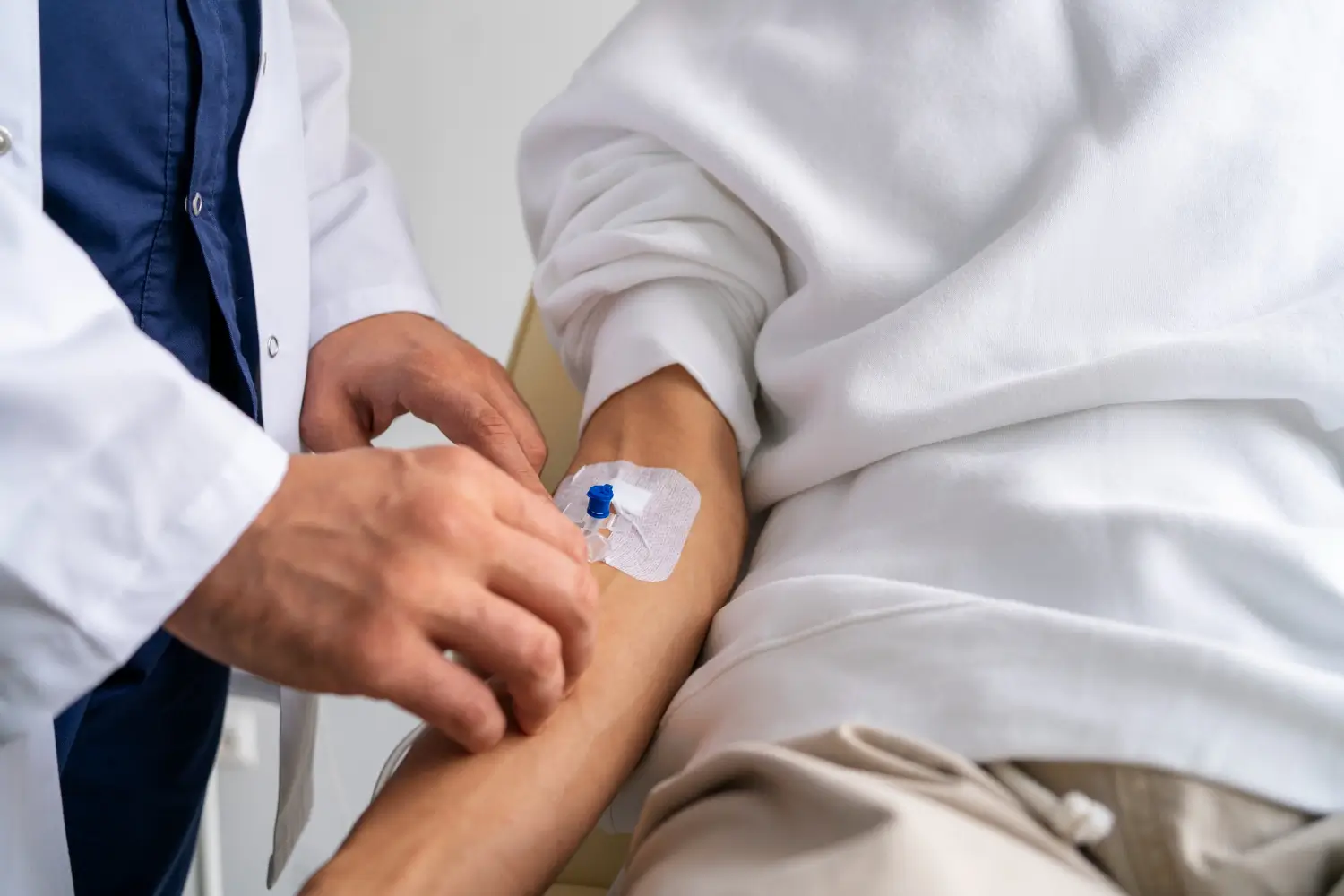 A medical professional checking the needle inserted on a patient.