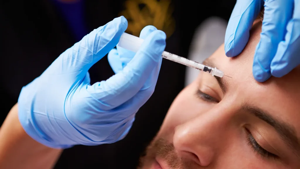 A male individual receiving a botox injection for their frown lines.