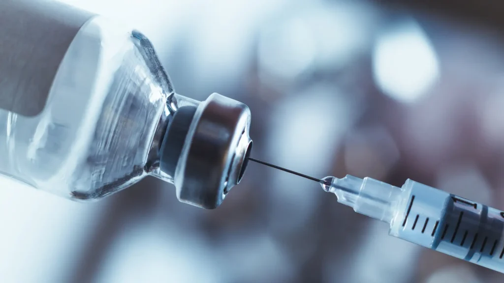 A close-up shot of a syringe inserted to the vial.