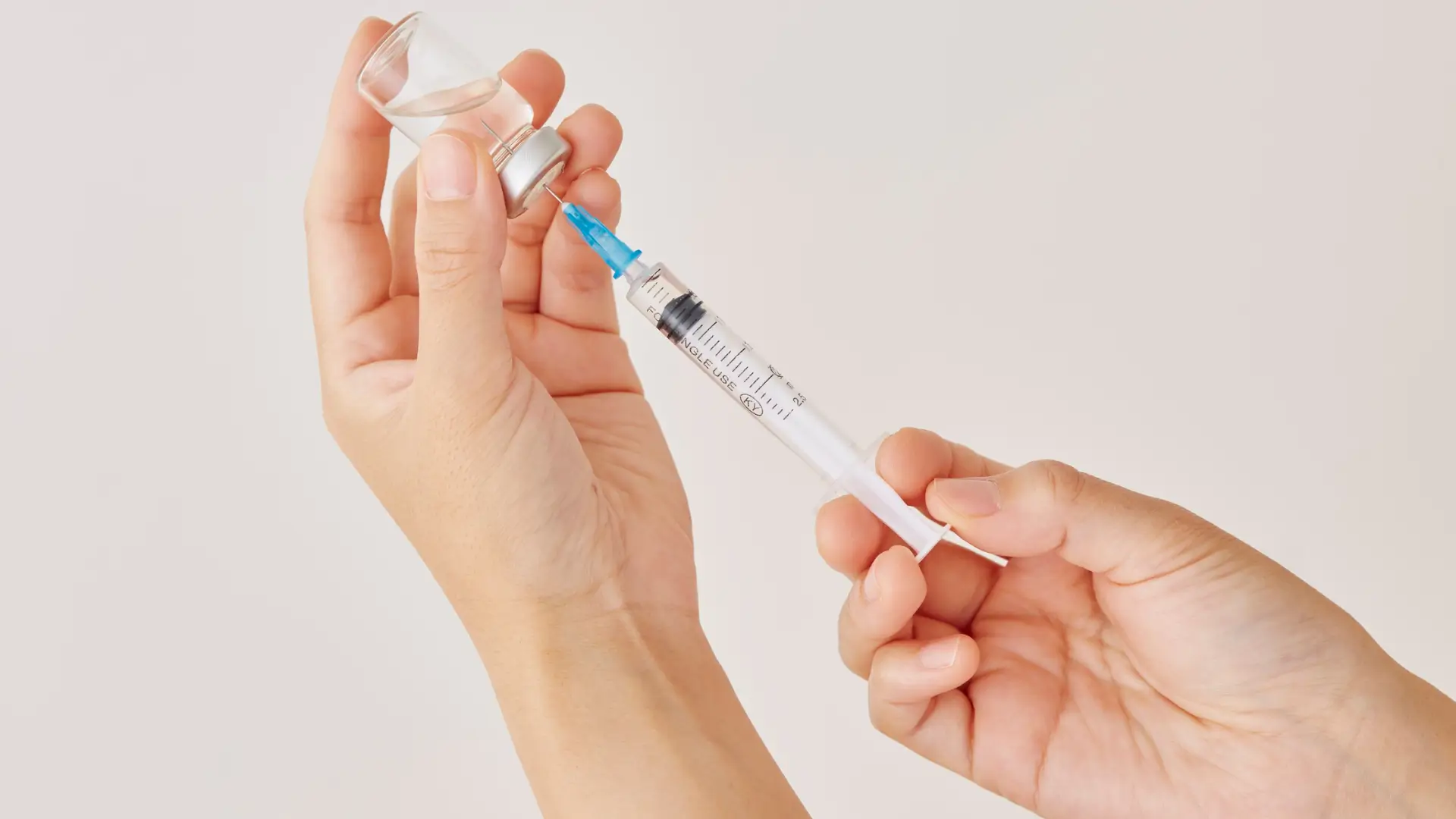 A medical professional transferring the vial solution's to a syringe.
