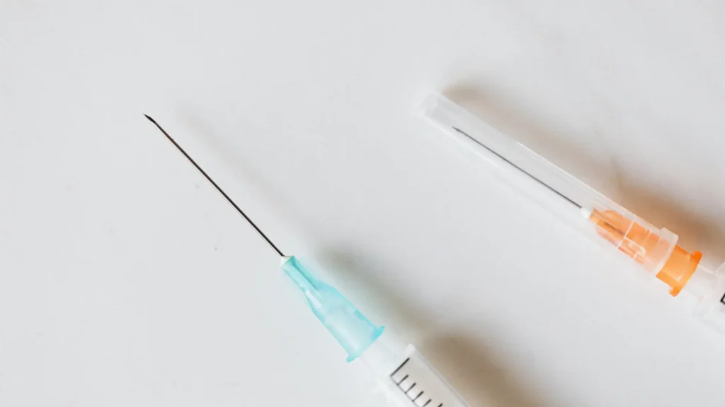 Two injection syringes on a flat white surface.