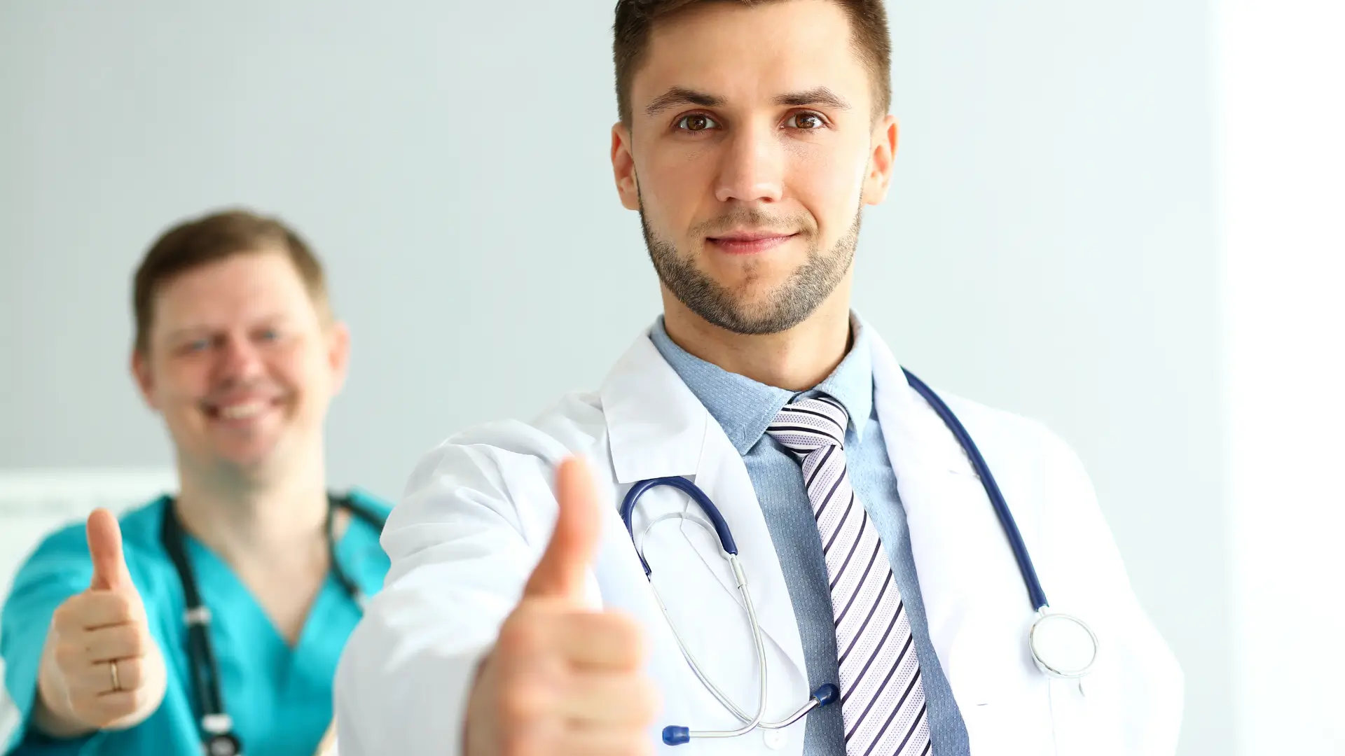 Two medical professionals posing for a thumb-up.