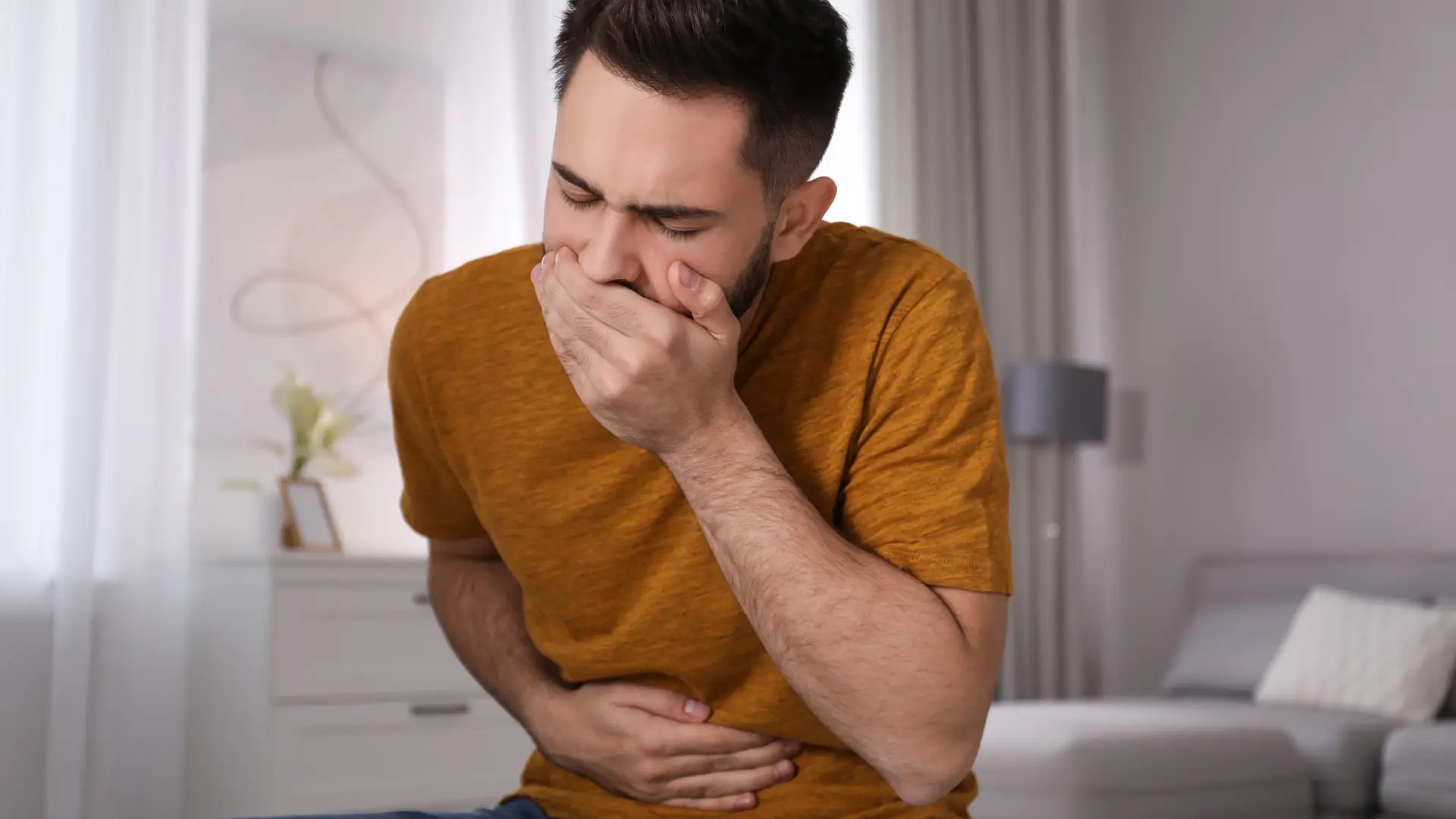 A male individual dealing with nausea, like one of the common Mounjaro side effects.