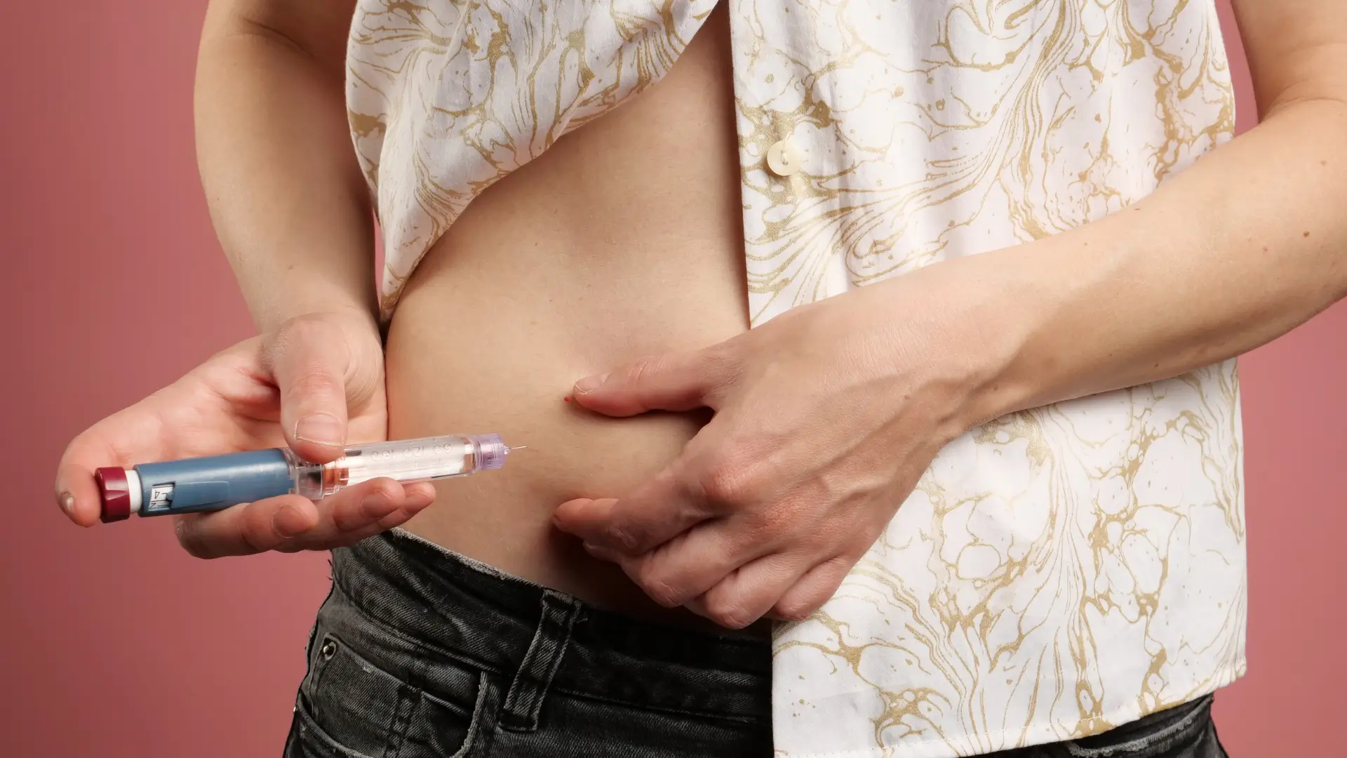 An individual self-administering a GLP-1 receptor injection to their abdomen.