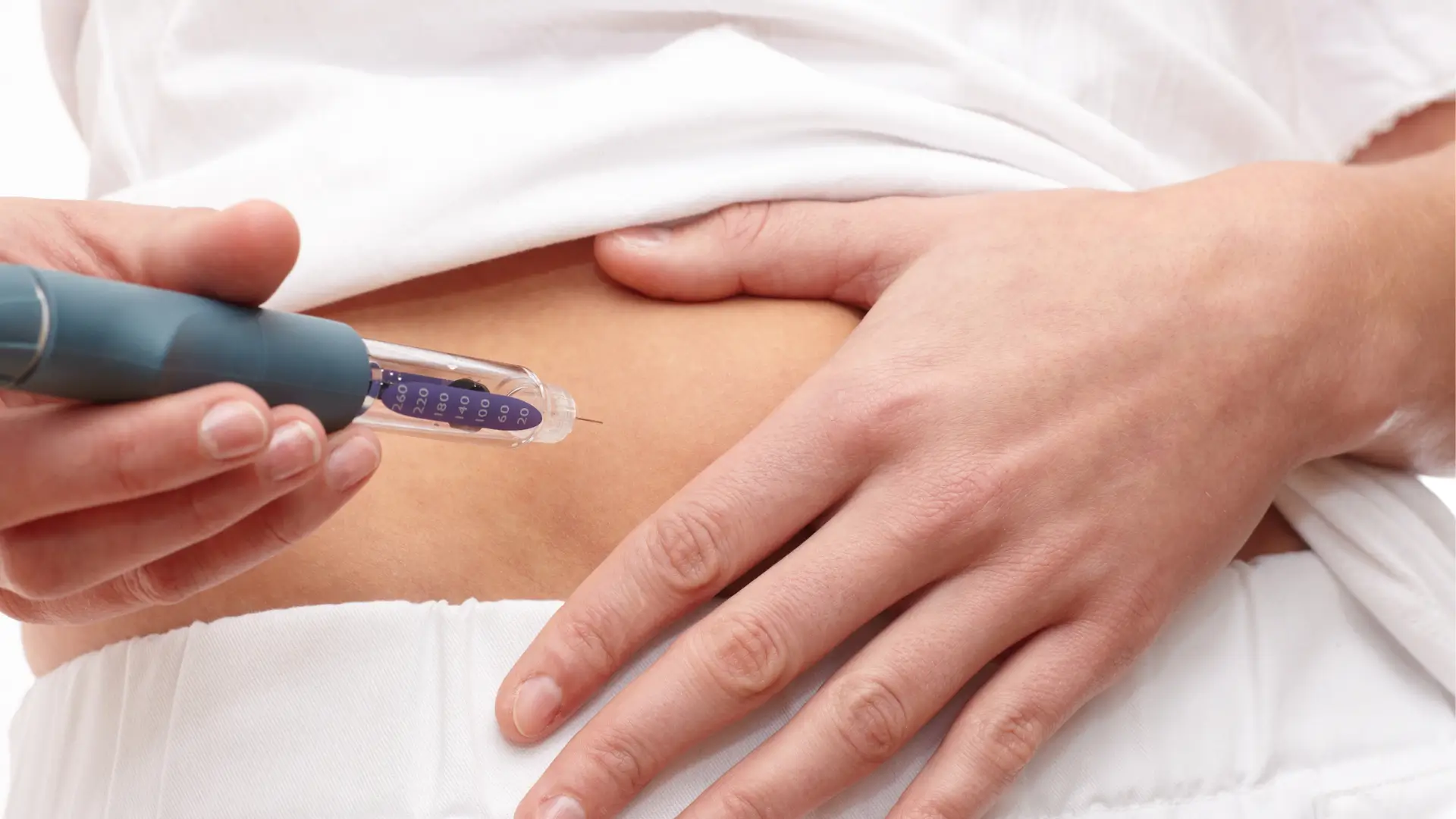 An individual administering a self-injection pen medication on their abdomen, similar to how Mounjaro is given.