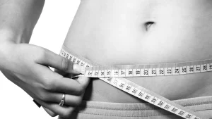 An individual measuring their waist after using GLP-1 receptor injections, like Mounjaro.