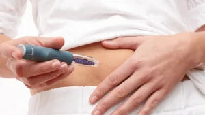An individual administering a self-injection on their abdomen.