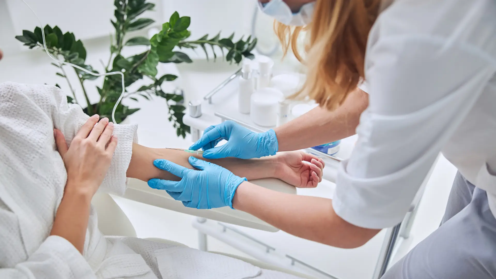 A medical practitioner administering an IV infusion drip on a patient in a NAD+ therapy clinic.