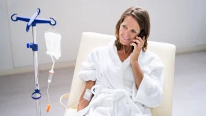 A patient undergoing an IV infusion like NAD IV therapy, while talking to someone on their smartphone.
