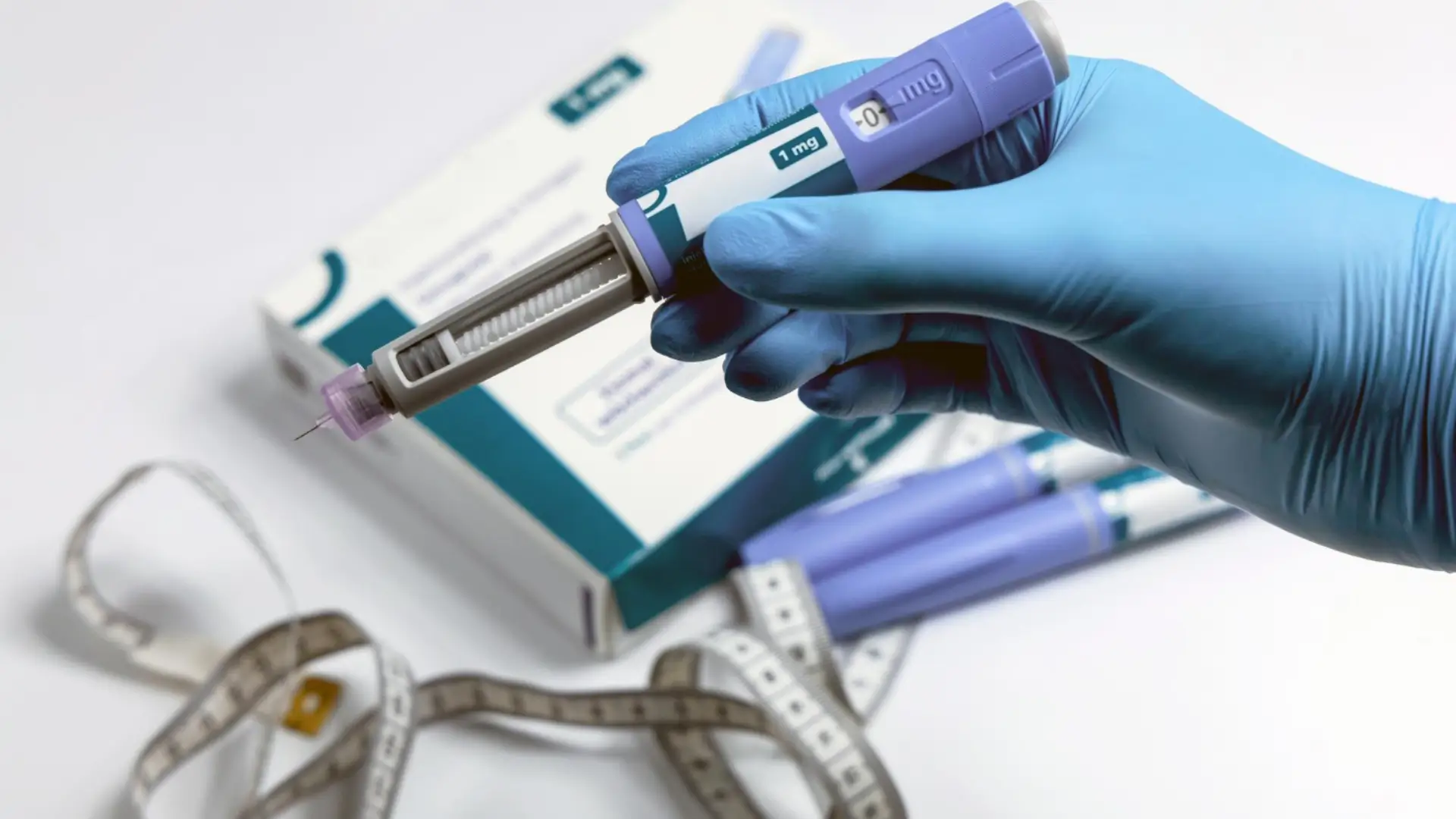 A hand wearing surgical gloves holding an Ozempic injection.