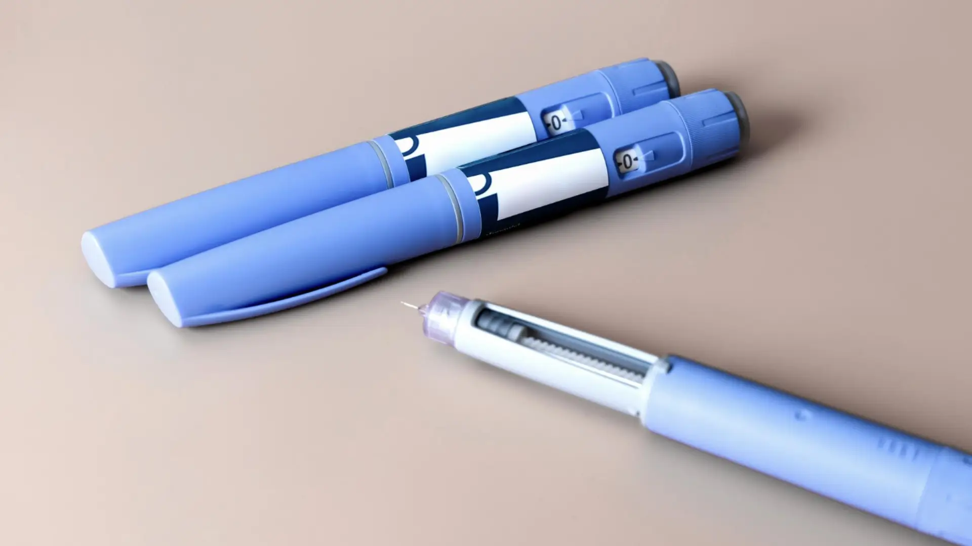 Three Ozempic pens on '0' dosage placed on a brown surface.
