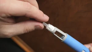 A close-up shot of an individual removing the needle cap of an Ozempic injection.