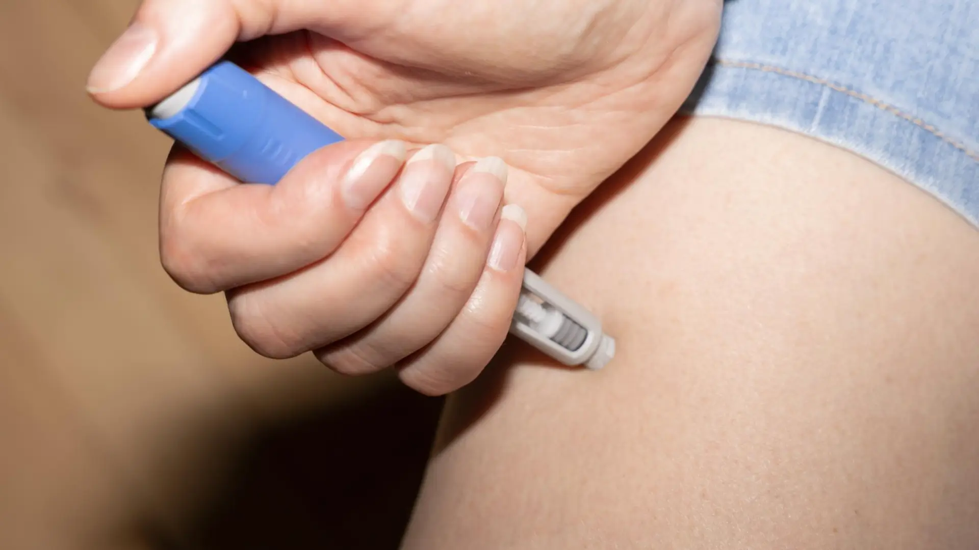 An individual administering an Ozempic injection on their upper thigh.