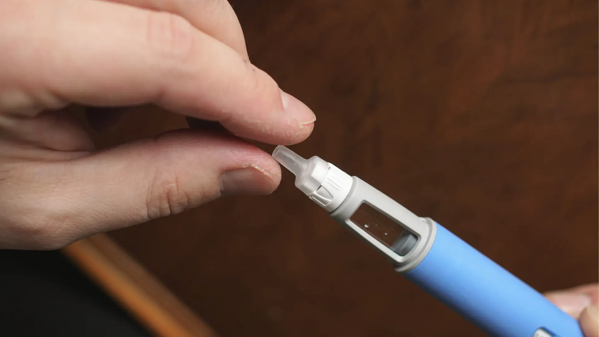An individual preparing the needle of an Ozempic pen injection before administration.