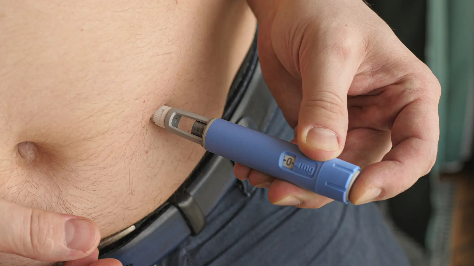 An individual administering an Ozempic self injection pen on their abdomen to manage their blood sugar control.