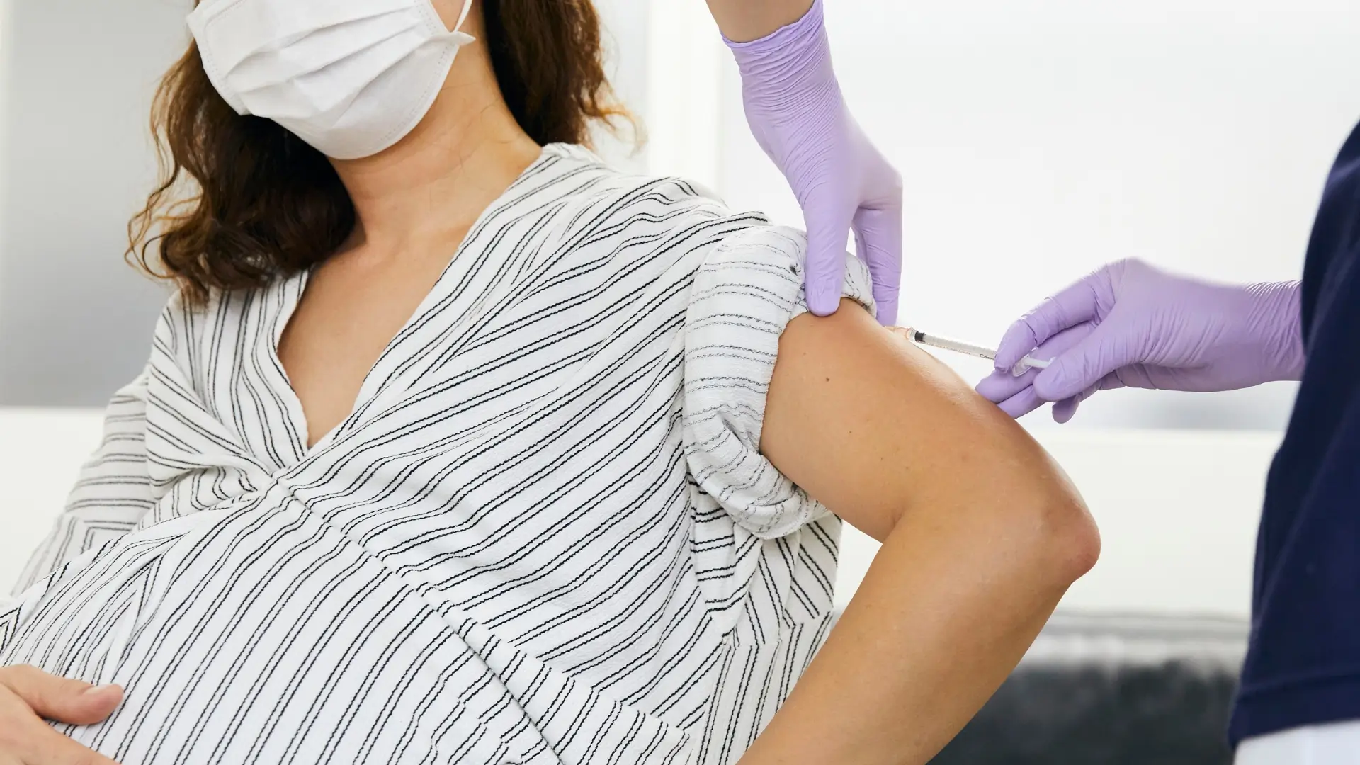 A healthcare professional giving an injection to a pregnant individual, like administering Xolair injections.