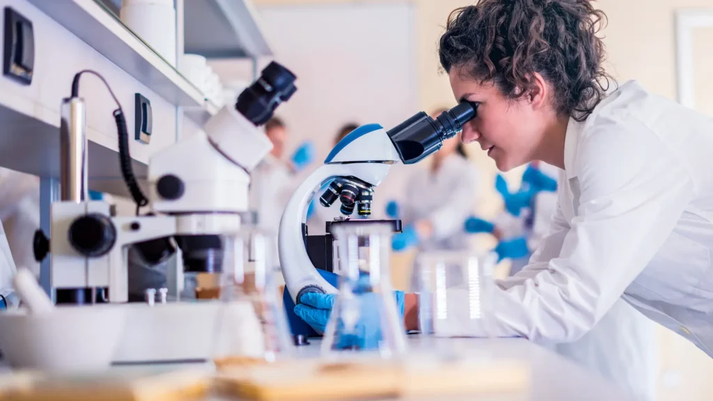 Researcher using a microscope in a laboratory, representing research studies and preclinical data on Ipamorelin side effects.