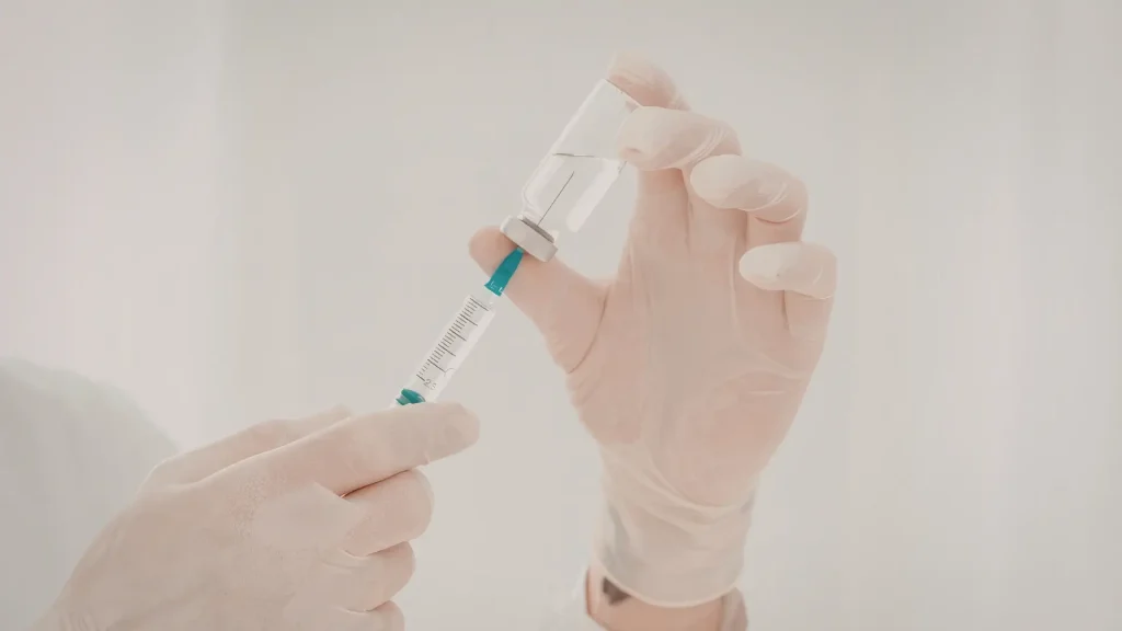 A medical professional transferring the vial's solution to a medical injection before administering an osteoporosis treatment.