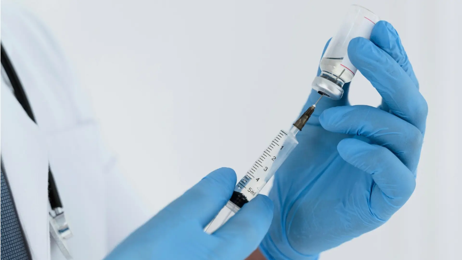 A medical professional transferring the vial's content to a syringe in choosing the safest injection for osteoporosis for their patient.