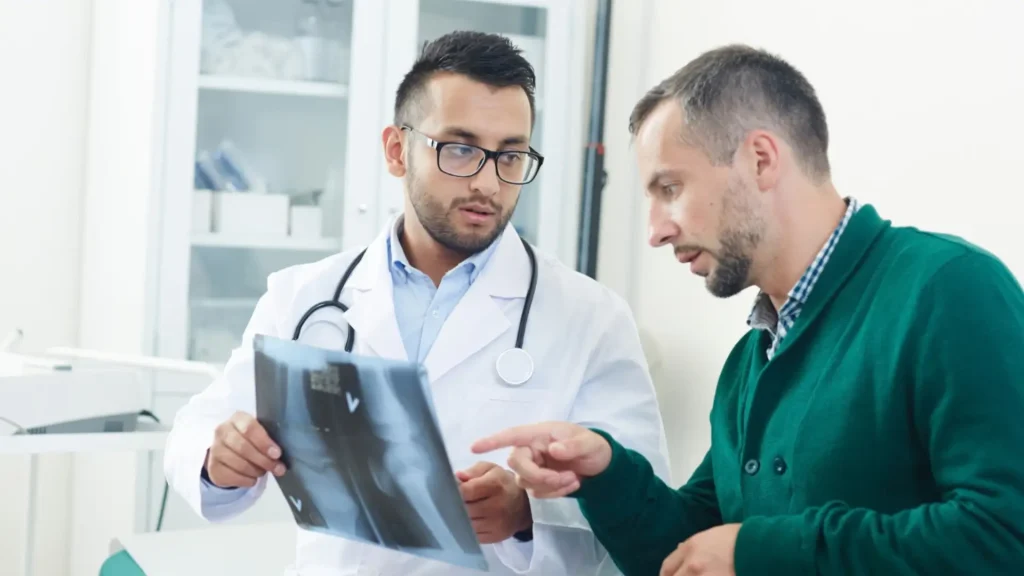 A medical professional explaining an x-ray result to a patient for their osteoporosis treatment.