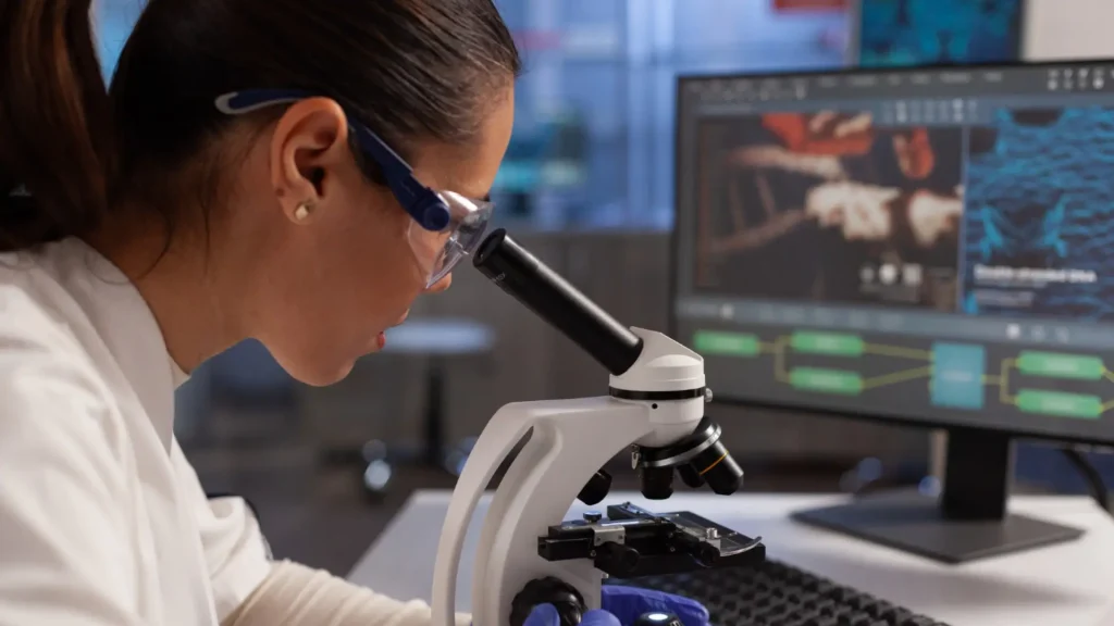 A researcher working on microscope for cell illustration of muscle development of Ipamorelin research peptide on computer screen in chemical laboratory.